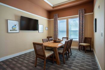 A dining room with a table and chairs and a television